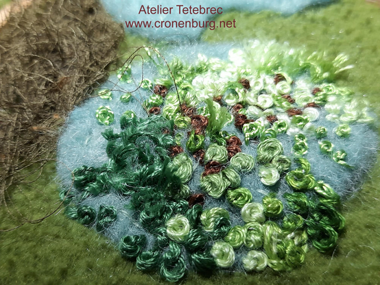 An old olive green polar fleece scrap with embroidery on a bright felted piece. The embroidery is done in French knots in chaotic order and sizes, in different green shades and some brown. The chaos gives a more natural aspect. The felt (which will be completely covered) gives a 3-D-effect.