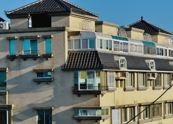 这是一座多层住宅楼，配有阳台和阳光房，建筑风格现代，天色晴朗。