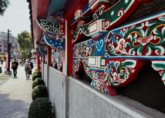 色彩鲜艳的传统建筑装饰细节，街道上有人行走，背景是城市建筑和树木。