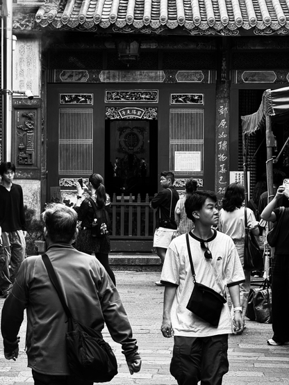 这是一个黑白照片，显示许多人在一座传统建筑前前行或拍照。