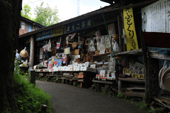 An old, grimy souvenir shop.
Various souvenirs are piled high on the wall facing the narrow street.