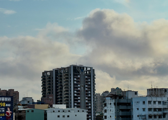 A city skyline with modern and older buildings under a cloudy sky.
