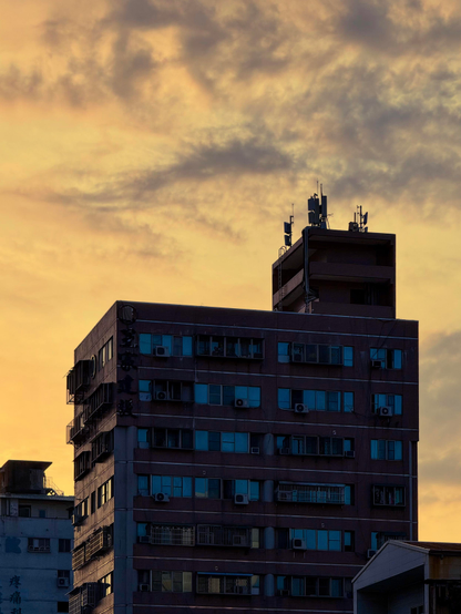 这是一栋多层建筑，夜幕下的城市天际线，背景是金色的云彩。