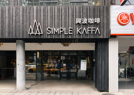 Storefront with signage reading "Simple Kaffa" and Chinese characters, featuring a black wooden facade and glass entrance door.