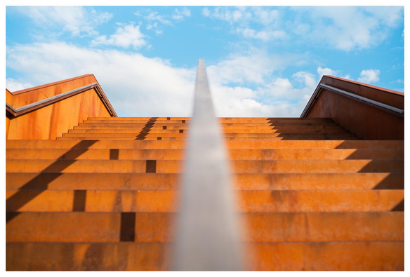 Verrostete Treppe und Handläufe, im Hintergrund Himmel.