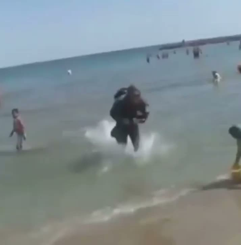 un soldat en tenue débarque sur la plage, dérangeant les baigneurs