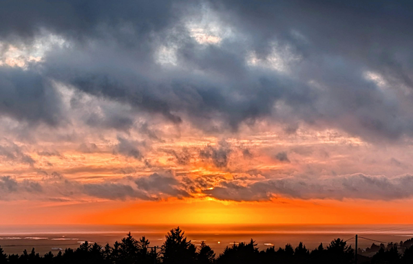 A very orange sky along the horizon at sunset. Dark clouds above. 