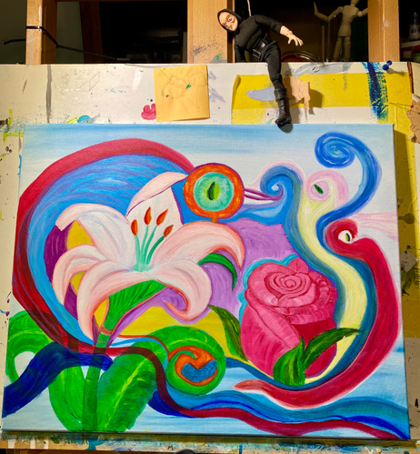 Medium size stretched canvas on an easel in front of a splash board, with an Igor doll stabilizing the canvas with a foot. 

The painting is a red rose bud and a white and orange lily, surrounded by swirling colors and possibly eyes. Plants man, they’re always watching…