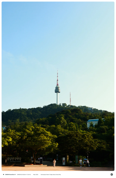 남산골한옥마을에서 바라 본 남산타워. 공원 한 가운데 사람이 걸어나가고 있음.