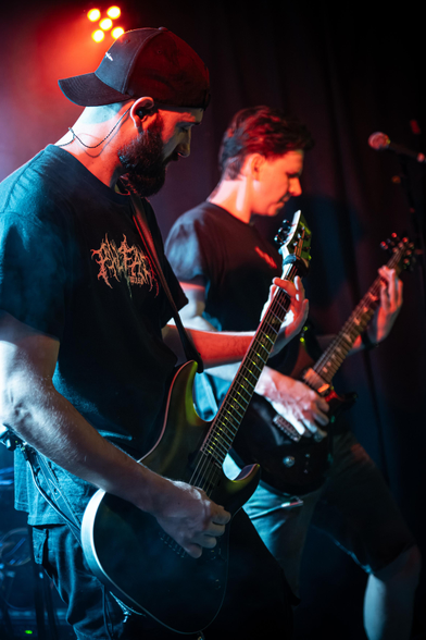 Das Bild zeigt die Gitarristen der Band Lunar Fall - Dany und Timo -, die mit ihren Gitarren in den Händen auf der Bühne voreinander stehen.