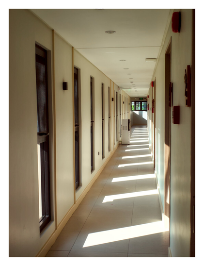 A long, empty hallway with bright sunlight streaming through a row of narrow windows, casting distinct rectangular patterns of light across the tiled floor. - Google Gemini 3.1 Pro Preview