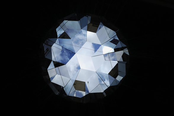 Blick nach oben in ein Kunstwerk des dänisch-isländischen Künstlers Olafur Eliasson in Hamburg: Der Himmel, Wolken und zum Teil die umgebenden Gebäude werden in der Mitte des Fotos wie bei einem Kaleidoskop in dreieckigen Flächen gespiegelt. Der Rest des Bildes ist dunkel, fast schwarz.

 A view upwards at a work of art by the Danish-Icelandic artist Olafur Eliasson in Hamburg: the sky, the clouds and, to some extent, the surrounding buildings are reflected in triangular shapes in the centre of the photograph, as if through a kaleidoscope. The rest of the image is dark, almost black.