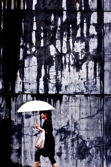 person with a white umbrella against a rain stained wall