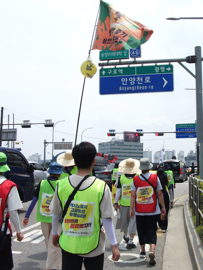 구로역 방향으로 행진하는 행진대오. “동양미래대학 앞” 표지판에는 “안양천로(우측)”라고 큰 글씨로 써있다. 작은 글씨로는 “(전방)구로역”, “광명(우측)”.