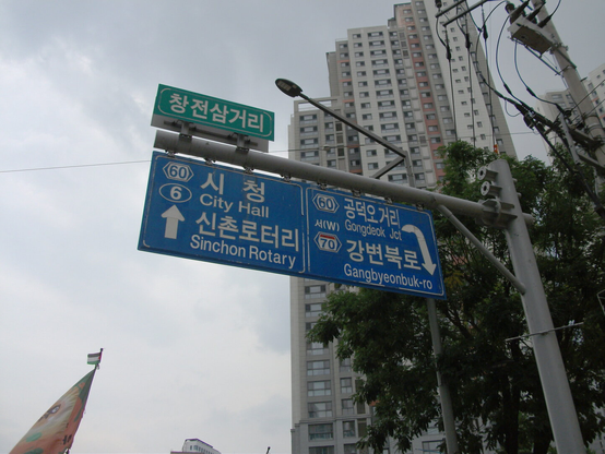 교통표지판. “(전방)시청, 신촌로터리”, “(우측뒤쪽)공덕오거리, 강변북로”.