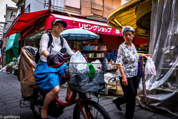 Una dona gran que camina mira de reüll una dona que va amb bicicleta i li passa pel costat.