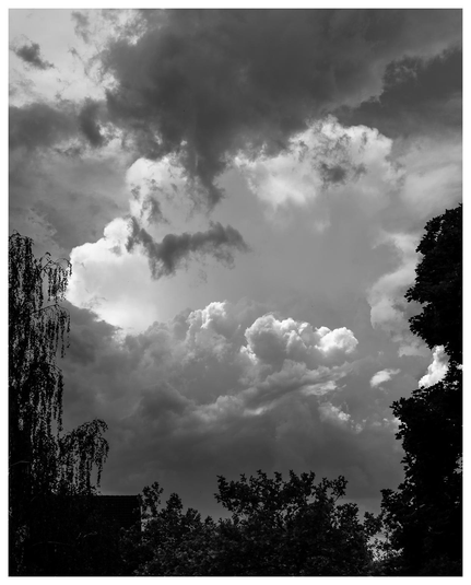 50 Shades of Gewitterwolkengrau zwischen Bäumen und Häusern durchfotografiert.