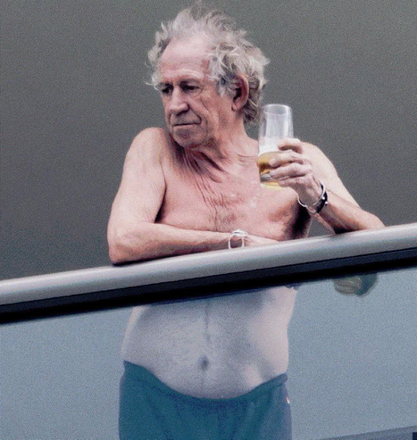 le guitariste du groupe rock The Rolling Stones, torse nu sur son balcon, tenant un verre de bière