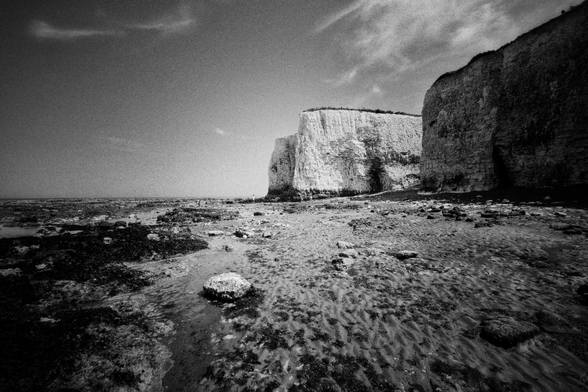 A monochrome photograph depicting cliffs and the sea.