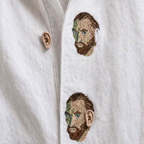 a white shirt with two van gogh heads stitched on it. One is missing an ear. The ear is the button which is detached because the shirt is open at one point. 