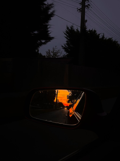 sunset in the wing mirror while driving into the night