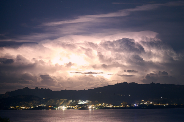 The photo shows Lightning in the clouds over a bay at the sea in the north of Sardegna.