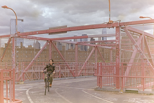 A man was riding an old commuter bike around a curve towards me, beneath thin red steel beams that frame the downtown Manhattan skyline
