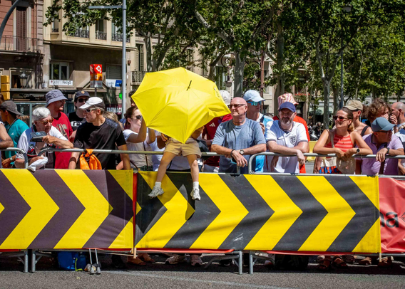 Cames de nen/a petit/a que sobresurten sota un paraigües groc entre el públic assistent a la contrarellotge de Barcelona de la primera etapa del Tour.