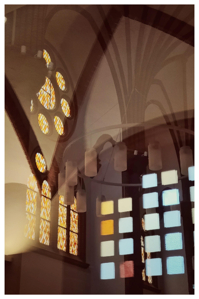 Farbfoto im Hochformat mit weißem Rand. Zu sehen sind Spiegelungen verschiedener, teilweise bunter Kirchenfenster, Lampen und Gewölbedecken in der Scheibe einer Glastür. Es ist nicht genau zu erkennen, was Spiegelung ist und welches Fenster sich wo befindet. Das Foto ist in bräunlichen und gelblichen Tönen gehalten. 