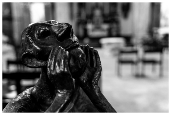 Ein (wie ich vermute) Bronzeguss eines Mannes mit großer Nase und glupschigen Augen. Er sieht nach oben und scheint den Kopf auf die seitlich angelegten Hände zu stützen.