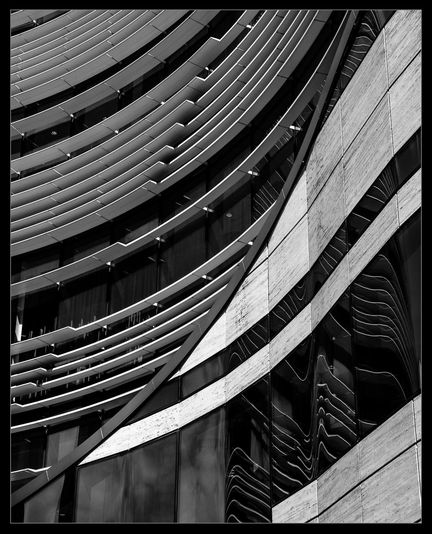 Detail einer geschwungenen Fassade eines modernen Büro/Geschäftsgebäudes. Speziell sind horizontal angeordnete Lamellen und die spiegelungen in den geschwungenen Scheiben.
