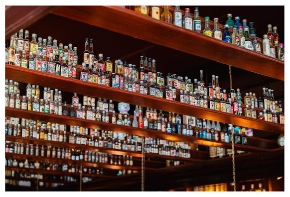 Hunderte (!) unterschiedlicher (!!) kleiner Schnaps und Likörflaschen stehen adrett aufgereit auf Regalen unter der Decke einer Bar.