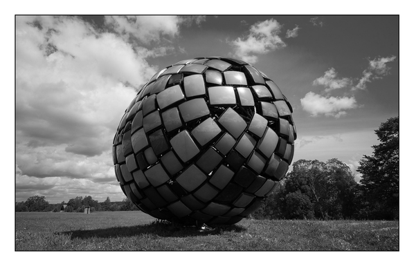 Große runde Skulptur aus alten Röhrenfernsehgeräten auf einer Wiese.