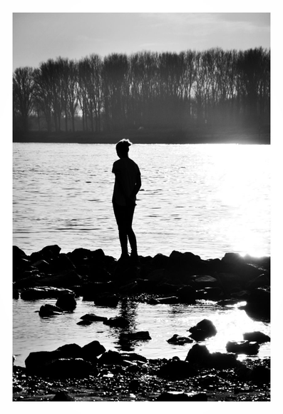 Die Sonne geht unter. Eine Frau steht an einem Fluss.
