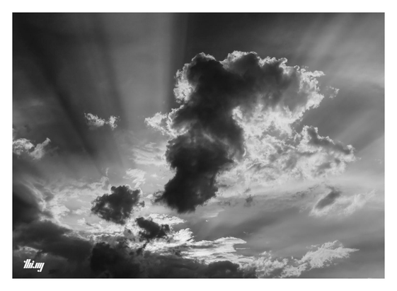 B&W photo of storm clouds with spectacular light shafts emanating from behind the lower cloud layers and across the sky