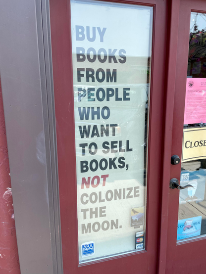 A sign in my local bookstore that says“ buy books from people who want to sell books, not colonize the moon “