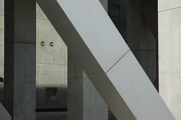 A photo of a large concrete building with modern architectural structures with concrete pillars and diagonal beams intersecting.