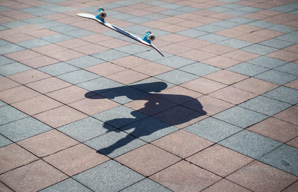 a street photo of a skateboard mid-air with the shadow of the skateboarder below