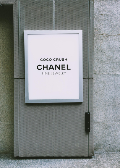 一块大型广告牌，展示“COCO CRUSH CHANEL FINE JEWELRY”，背景为现代建筑墙面。