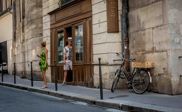 Parella sortint d'una botiga de barri, amb bicicleta aparcada contra la pared de l'edifici.