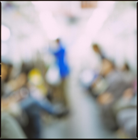 an out of focus shot of a woman in blue dress on a tokyo subway train