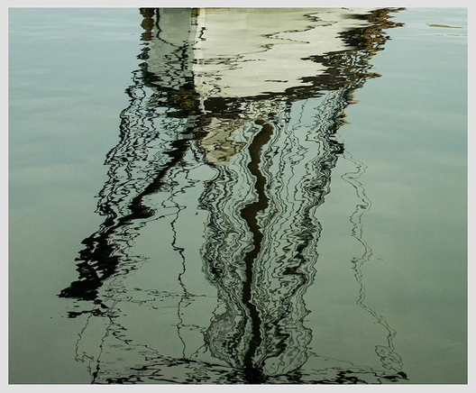 An abstracted image of the reflection of a nineteenth-century boat and its rigging - ropes, mast, etc - in almost still blue-green water. At the top of the image, the white of the boat itself outlined in way black lines; below, the black ink-like squiggles and undulations of the lines of the rigging in the water. 