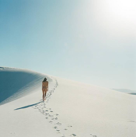 une personne marchant sur de vastes dunes de sable blanc, vraisemblablement dans un paysage désertique de gypse tel que le parc national des White Sands au Nouveau-Mexique
