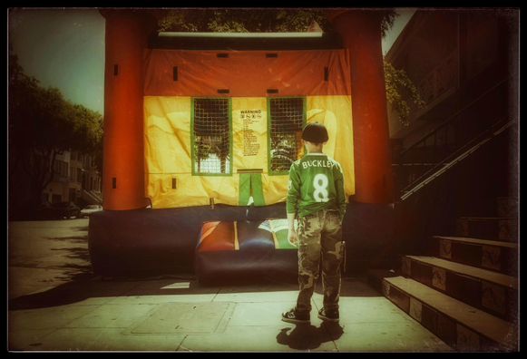 A picture from April 18th, 2010. Taken in the Mission, it shows a young lad standing on a sidewalk, looking at a giant, colorful castle bouncy house. The boy is reading all the warnings printed on the side of the house that spell out all of the things he is not supposed to do inside. It is a very long list. 

Buzzkill.

My proposal includes no rules. Let havoc reign.
