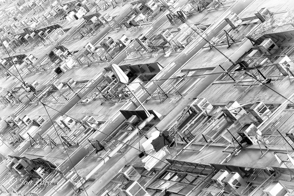 This is an abstract street photo in landscape format of a dutch angle view (the camera is tilted away from the horizontal or vertical) of the slightly overexposed front of an older, mid-rise, mixed use building. North Point Hong Kong (2014).

The entire photo is filled with the front facade of this building. While the camera is located in the street, angled along the front of the building from about 5 metres away and upwards, giving the appearance in viewing is that the building is tilting backwards, away from the camera, at an angle of 45º. The photo is slightly overexposed producing a mid-grey or silver look. The building's facade is continuous, extending for about 50m away from the camera and then out of view at the left edge of the photo. There is nothing uniform about the exterior of the building. In view are 8 floors with the ground floor hidden below the lower edge of the image. The upper floors are hidden above the top of the photo. Each floor is an untidy mess of non-matching windows, some open, some closed. Randomly placed external air con units. Washing racks, some with laundry drying, some without. In addition, in front of our building is a tall street light leaning happily at an angle of 45º to the right, plus numerous cables traversing the street below that carry the electrical power for the ancient trams that valiantly attempt to pass through the shoppers in the busy roadside market stretching along the street.

The term 'Dutch Angle' is believed by some to be a corruption of the German phrase 'Deutsch Angle' (Deutsch Winkel) due to the popularity of this style of camera shot in early German silent films. Fewer still, consider it based on the aeronautical term 'Dutch Roll' - Probably neither is correct. 